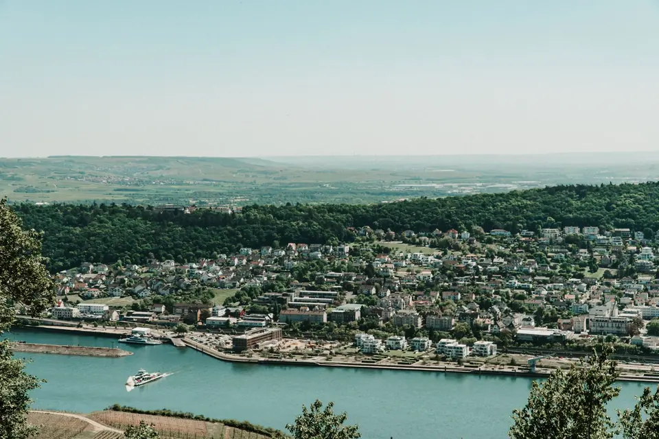 Eine malerische Luftaufnahme, die den Rhein und eine charmante deutsche Stadt umgeben von üppigem Grün zeigt.